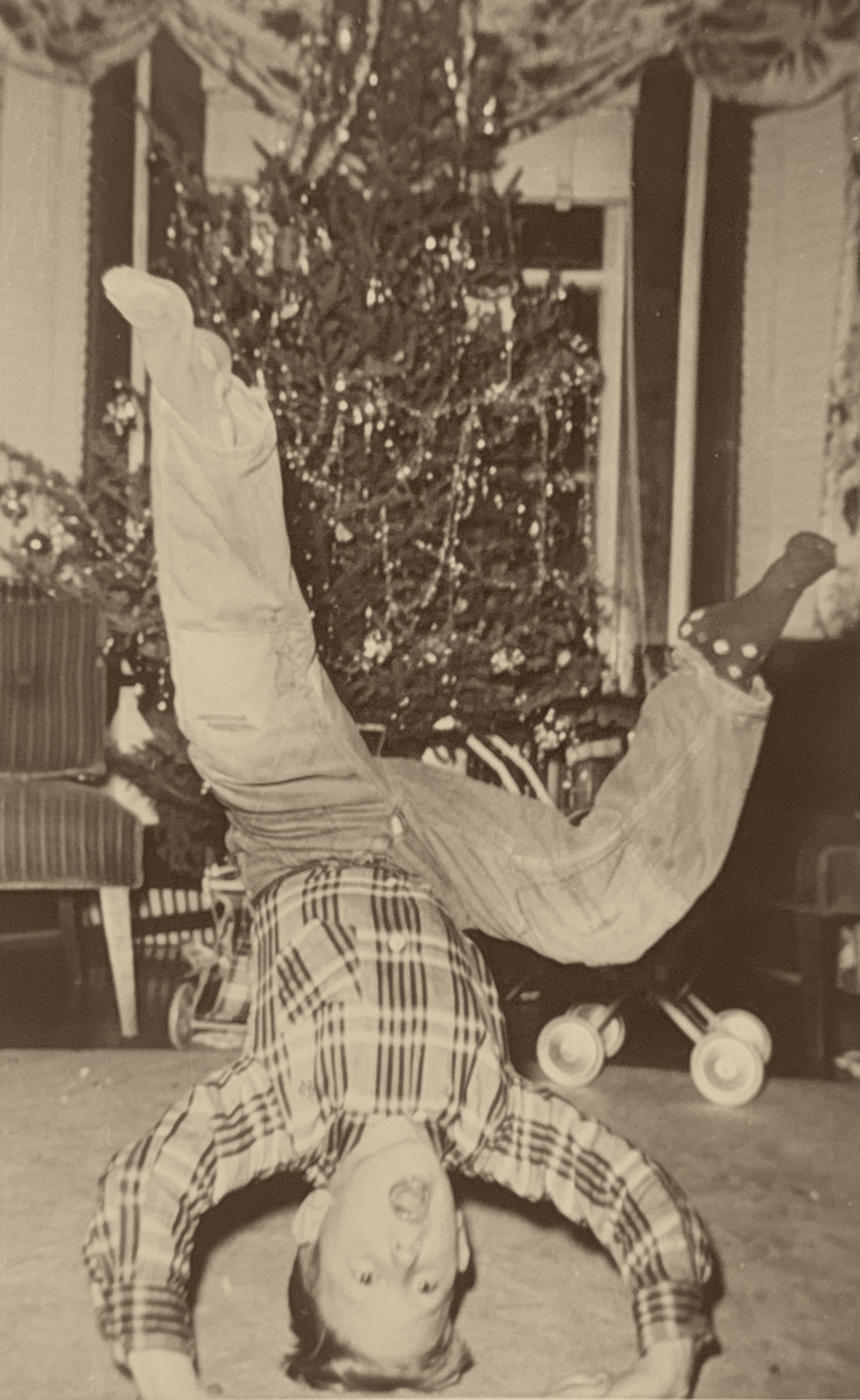 Dennis as a boy, doing a headstand in front of the Christmas tree